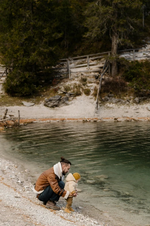 a man holding a teddy bear next to a body of water, girl of the alps, slide show, playing, dolomites