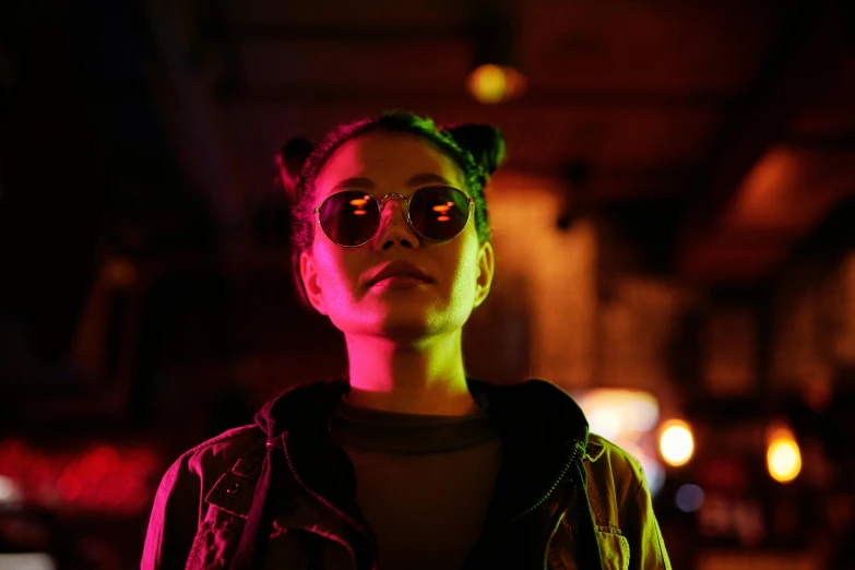 a woman standing in a dimly lit room, inspired by Elsa Bleda, trending on pexels, bauhaus, colorful neon lights, sunglasses on, teenage girl, movie still of the alien girl
