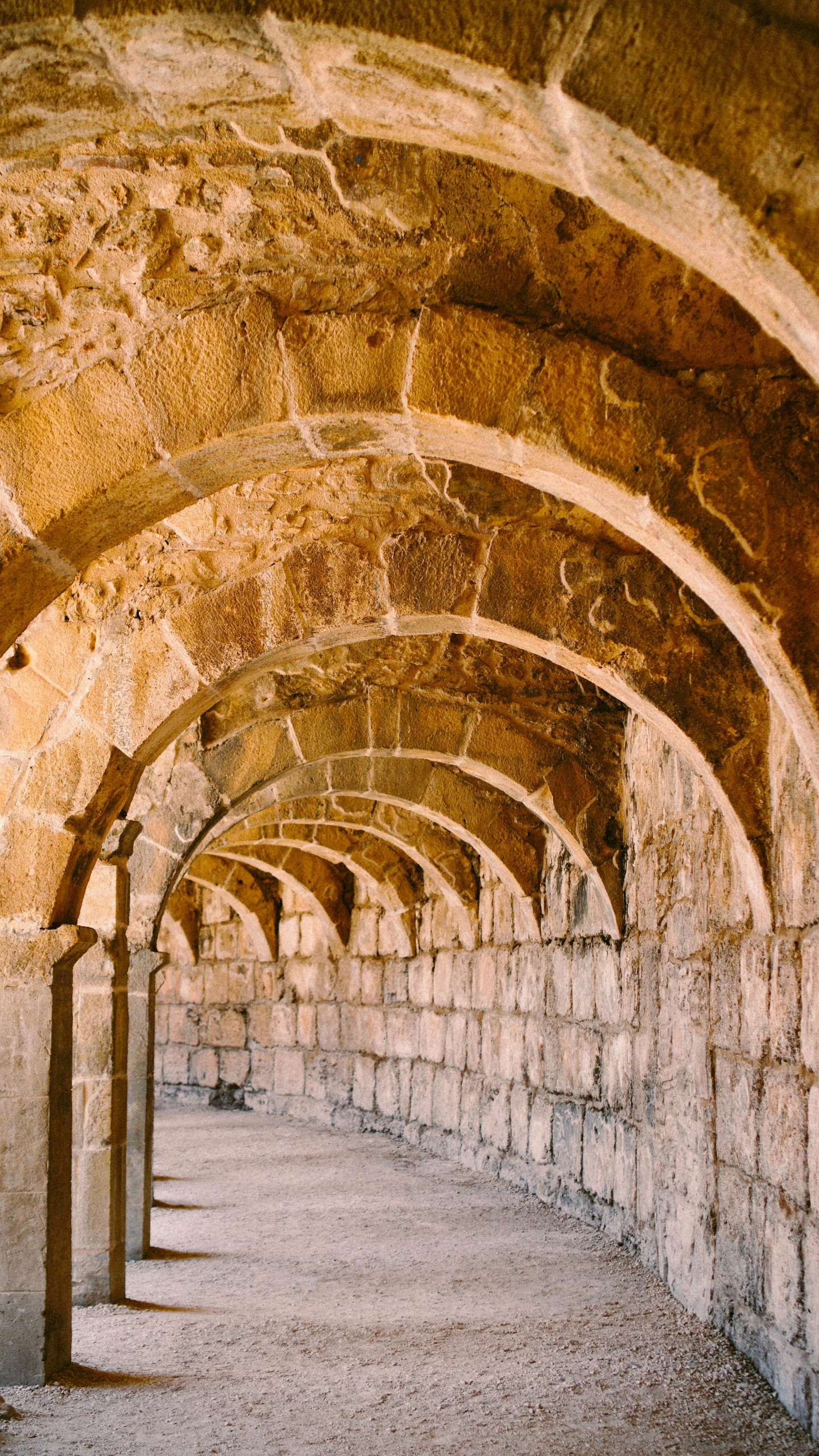 a row of arches in a stone building, an album cover, inspired by Modest Urgell, trending on unsplash, damascus, aqueducts, crypt, al - qadim