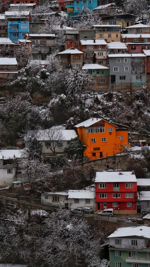 a group of houses sitting on top of a snow covered hillside, by Muggur, pexels contest winner, hurufiyya, vibrant but dreary orange, thumbnail, ap news photo, multiple stories