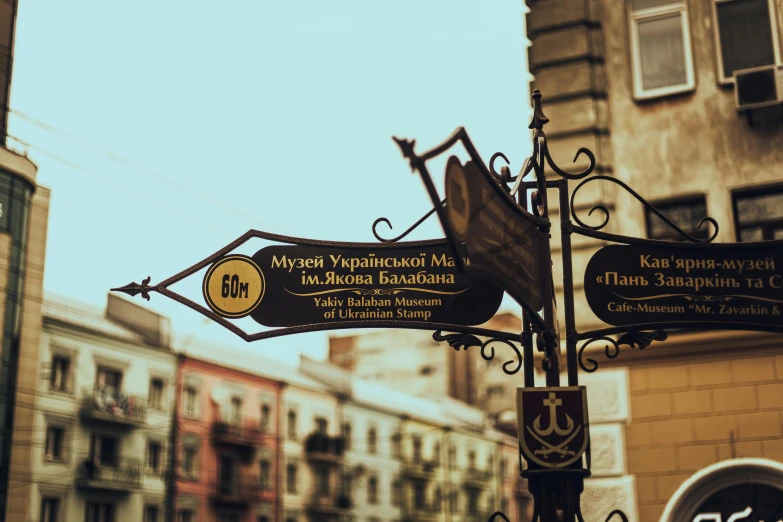 a close up of a street sign with buildings in the background, by Maksimilijan Vanka, pexels contest winner, art nouveau, byzantine, square, 000 — википедия, brown