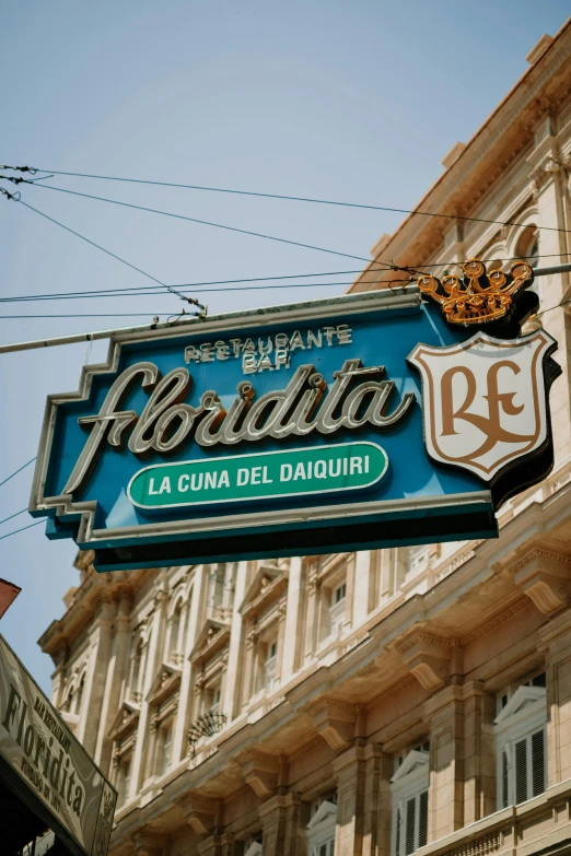 a restaurant sign hanging from the side of a building, flora, in a city with a rich history, profile image, el dorado