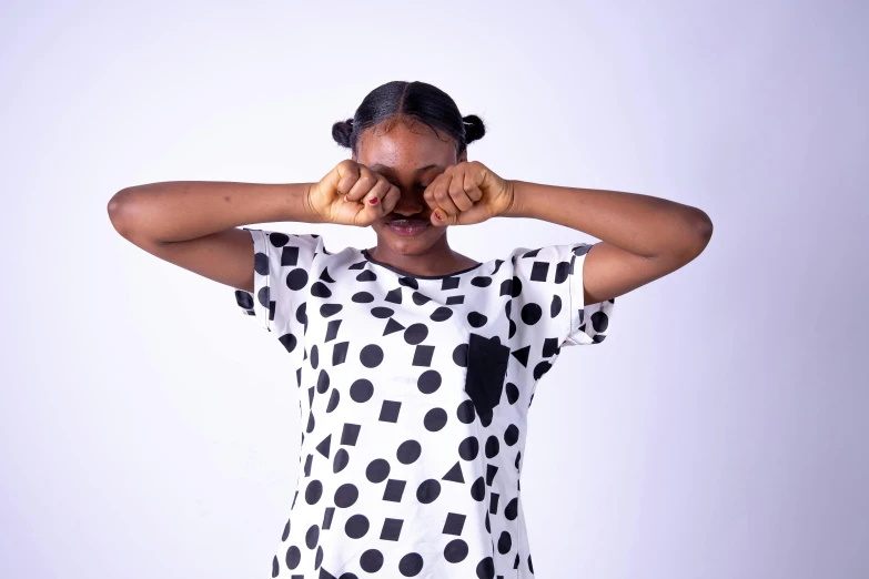 a woman covering her eyes with her hands, by Chinwe Chukwuogo-Roy, pexels contest winner, visual art, polka dot, graphic tees, silly playful fun face, white and black clothing