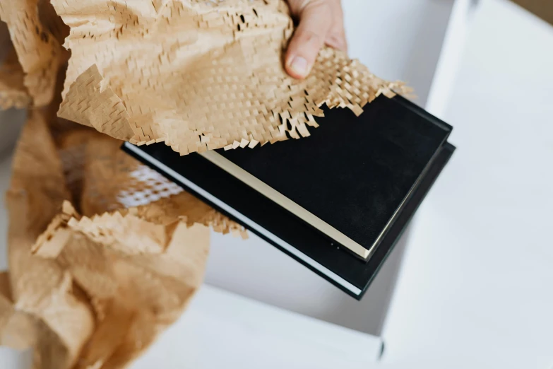 a close up of a person holding a book, an album cover, inspired by Hedi Xandt, pexels contest winner, natural materials, wrapped in black, deckle edge, cardboard