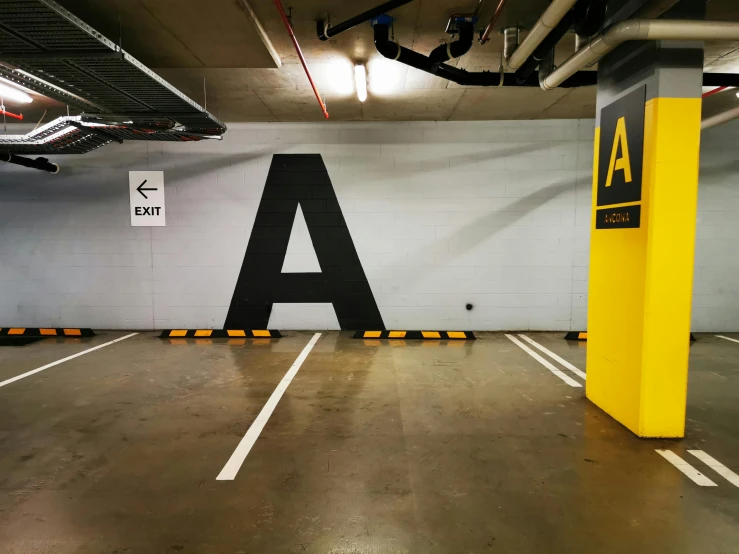 a parking garage with a large a sign on the wall, by Adam Rex, unsplash, temporary art, square, in chippendale sydney, floor b2, letter a