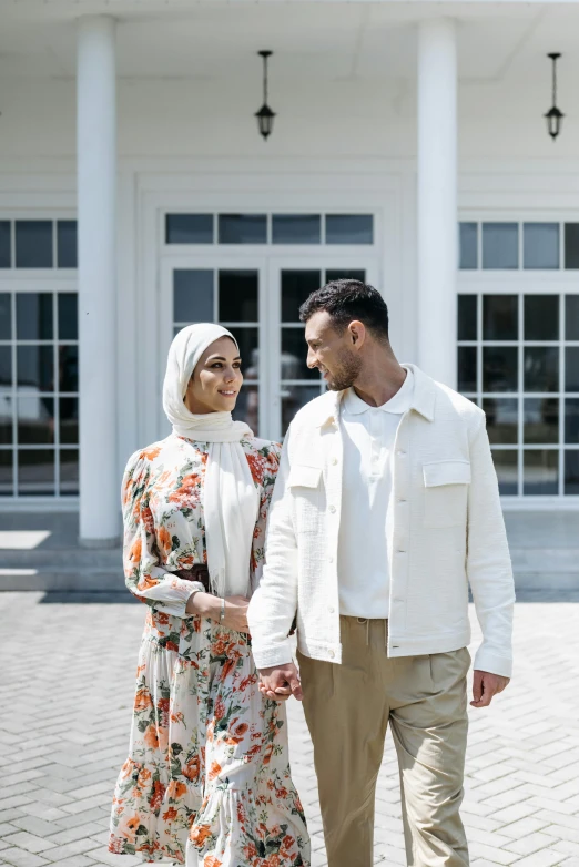 a man and a woman walking in front of a building, a colorized photo, pexels contest winner, hurufiyya, wearing white clothes, couple portrait, malaysian, background image