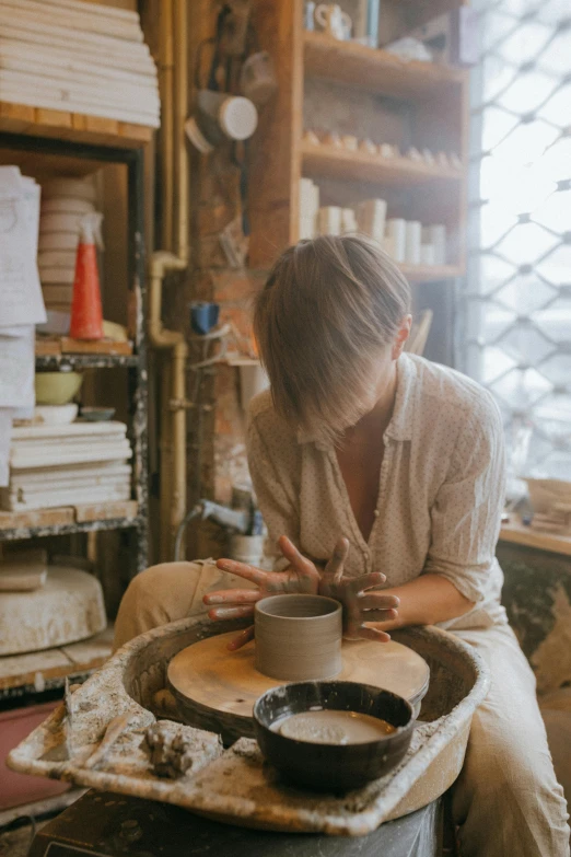 a woman is making a bowl out of clay, trending on pexels, arbeitsrat für kunst, cute woman, australian, sitting, professionally