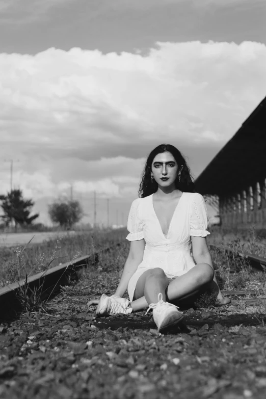 a black and white photo of a woman sitting on train tracks, by Lucia Peka, serial art, wearing white skirt, drag, yael shelbia, ((portrait))