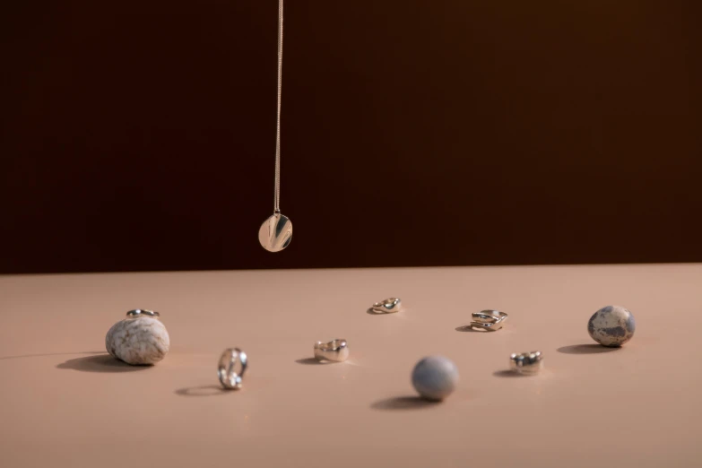 a bunch of balls sitting on top of a table, by Emma Andijewska, assemblage, platinum jewellery, floating beside planets, close-up product photo, strings