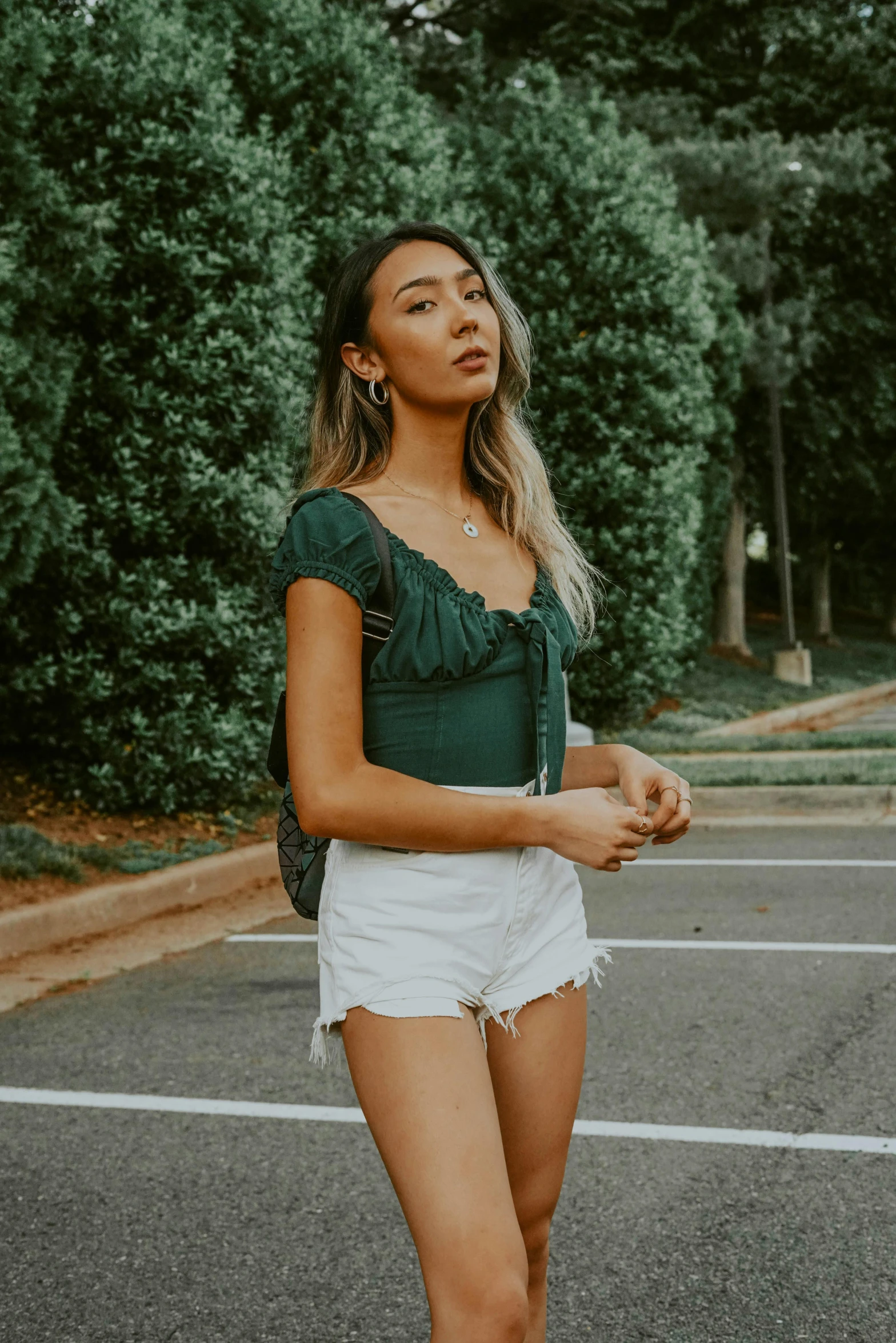 a woman standing in the middle of a parking lot, trending on unsplash, renaissance, dressed in a top and shorts, deep green, ruffles, with ripped crop t - shirt