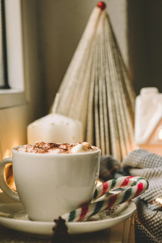 a cup of coffee sitting on top of a saucer, in front of a fireplace, whipped cream, holiday vibe, brown and cream color scheme