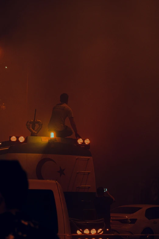 a group of people riding on top of a truck, an album cover, by Attila Meszlenyi, pexels, hurufiyya, smokey lights, concert footage, ( ( theatrical ) ), long shot from back