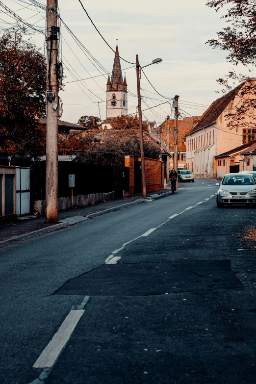 a street with cars parked on the side of it, by Adam Szentpétery, quaint village, cinematic morning light, churches, 8k 28mm cinematic photo