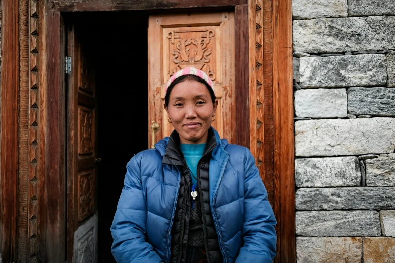 a woman standing in front of a wooden door, a portrait, pexels contest winner, hurufiyya, omar shanti himalaya tibet, avatar image, in front of the house, maintenance photo