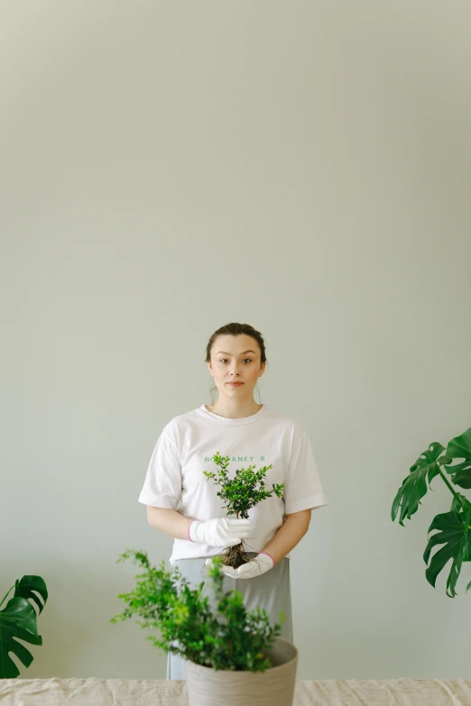 a woman standing in a room holding a potted plant, pexels contest winner, dressed in a white t shirt, avatar image, porcelain organic, high quality photo