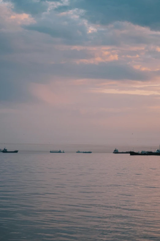 a group of boats floating on top of a body of water, unsplash, romanticism, soft lilac skies, black sea, shipping docks, predawn