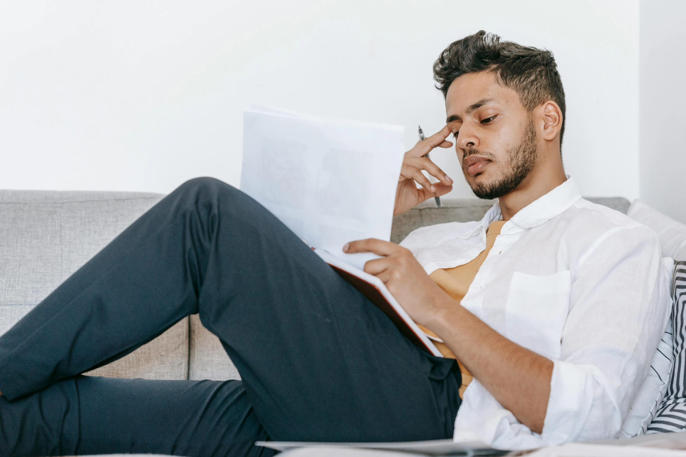 a man sitting on a couch talking on a cell phone, trending on pexels, academic art, writing on a clipboard, looking tired, mohamed chahin style, wearing business casual dress