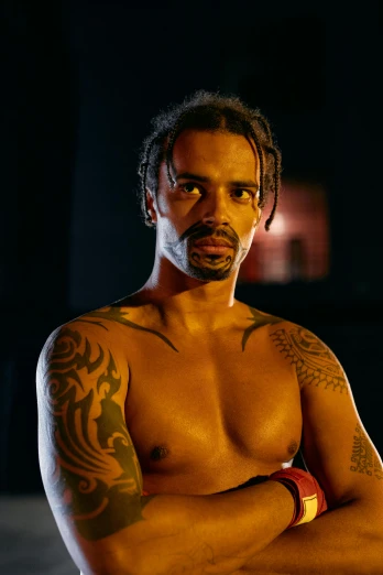 a shirtless man standing with his arms crossed, a tattoo, inspired by Gerald Kelly, in a boxing ring, pride, square, photo still