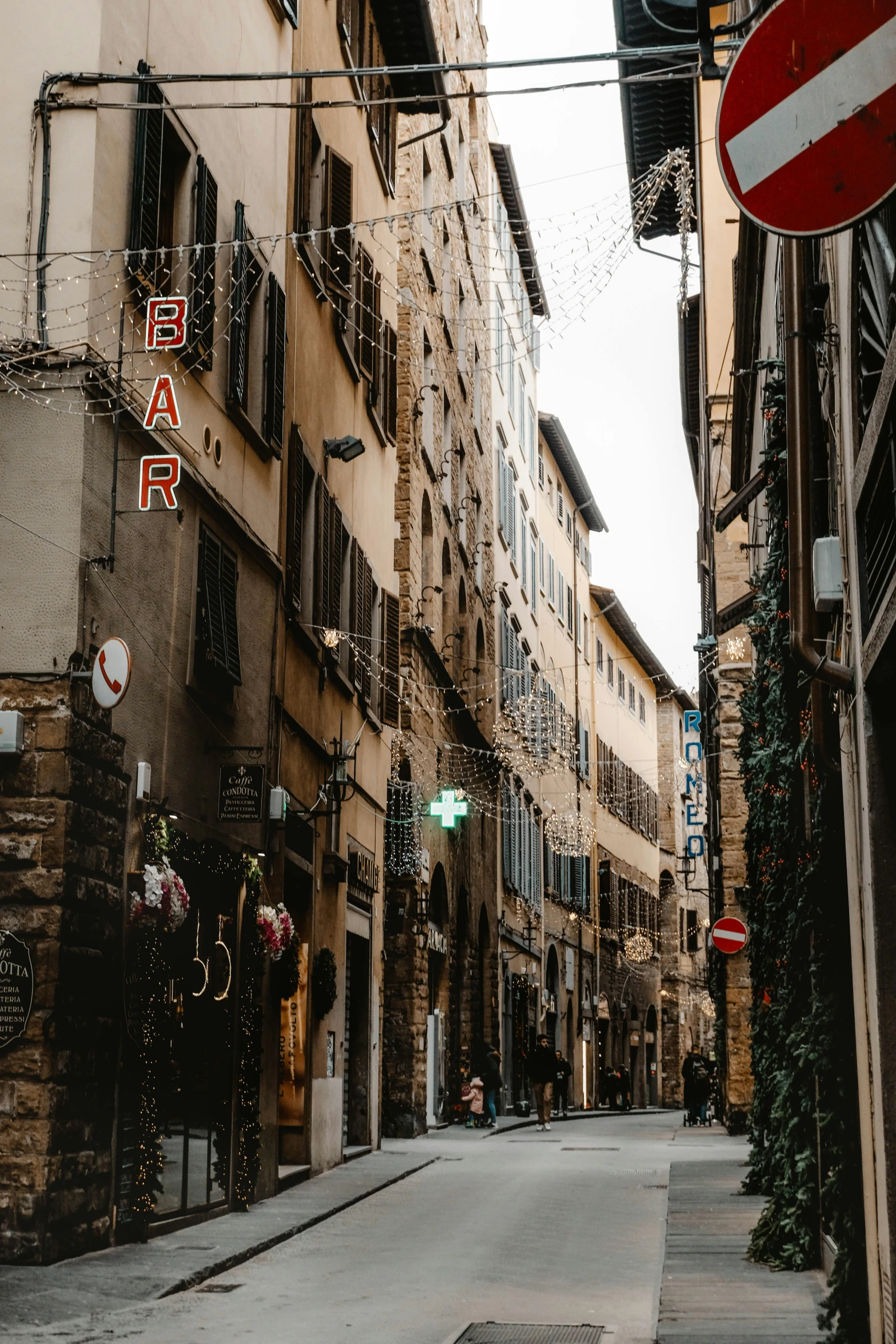 a red and white street sign sitting on the side of a building, a picture, by Alessandro Allori, pexels contest winner, renaissance, shady alleys, lots of shops, gif, florentine school