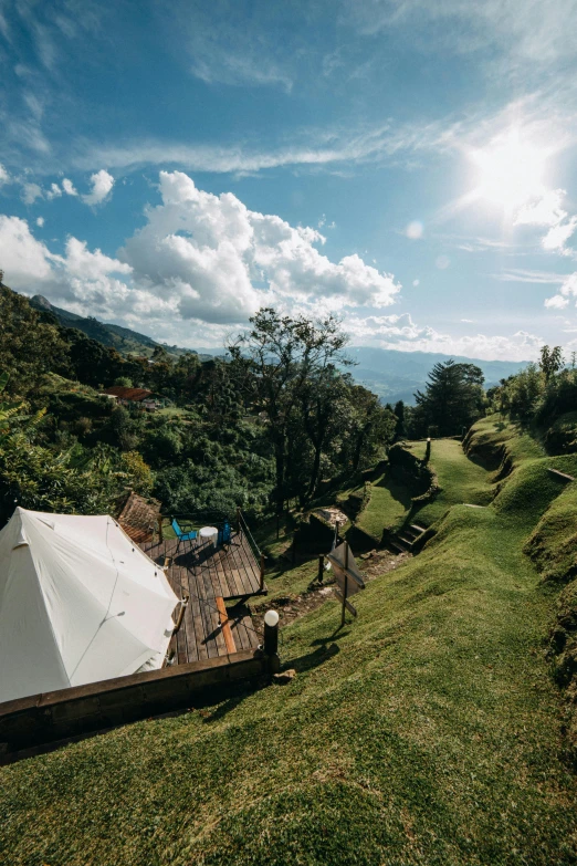 a white tent sitting on top of a lush green hillside, colombia, healing pods, flat lay, overhead sun