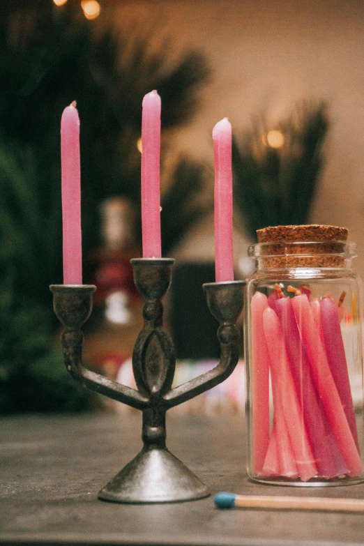 a couple of candles sitting on top of a table, pink magic, zoomed in, wands, medium close shot