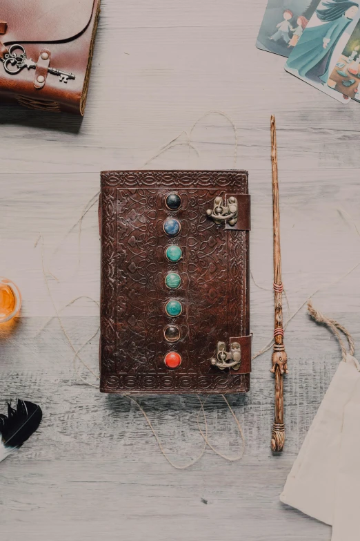 a brown book sitting on top of a wooden table, inspired by Fuller Potter, trending on pexels, embedded with gemstones, long trunk holding a wand, flat lay, thumbnail