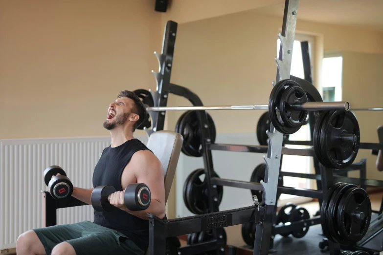 a man sitting on a bench in a gym, private press, avatar image, background image, colour photograph, shouting