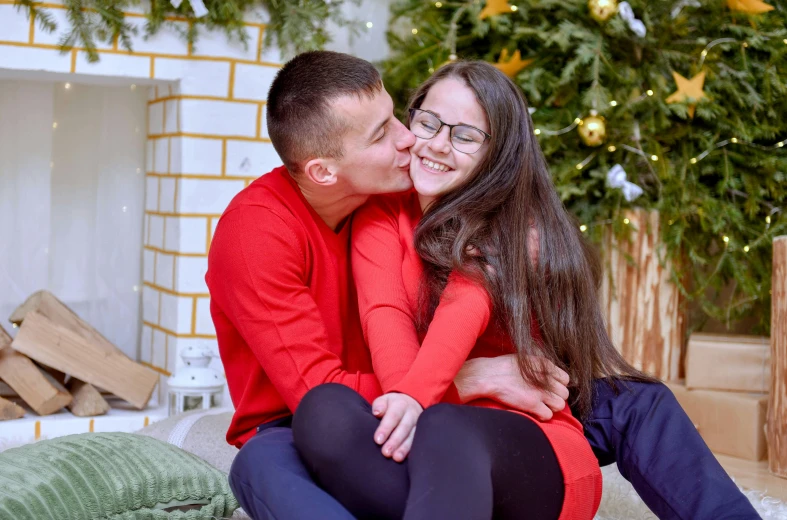 a man and woman sitting in front of a christmas tree, a picture, pexels contest winner, hurufiyya, peasant boy and girl first kiss, long hair and red shirt, avatar image, russian girlfriend