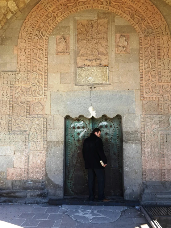 a man standing in front of a metal door, inspired by Osman Hamdi Bey, unsplash, romanesque, center of picture, cartouche, overlooking, information