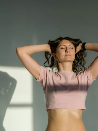a woman standing in a room with her hands on her head, trending on pexels, happening, sport bra and shirt, pink shirt, lorde, low quality photo