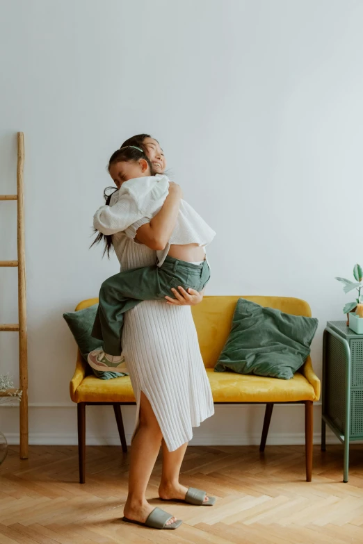 a woman holding a baby in her arms, unsplash contest winner, modernism, yellow carpeted, hugs, on a couch, leaving a room