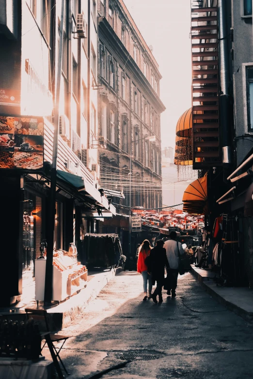 a group of people walking down a street next to tall buildings, a picture, pexels contest winner, istanbul, warm sunlight shining in, old shops, gif