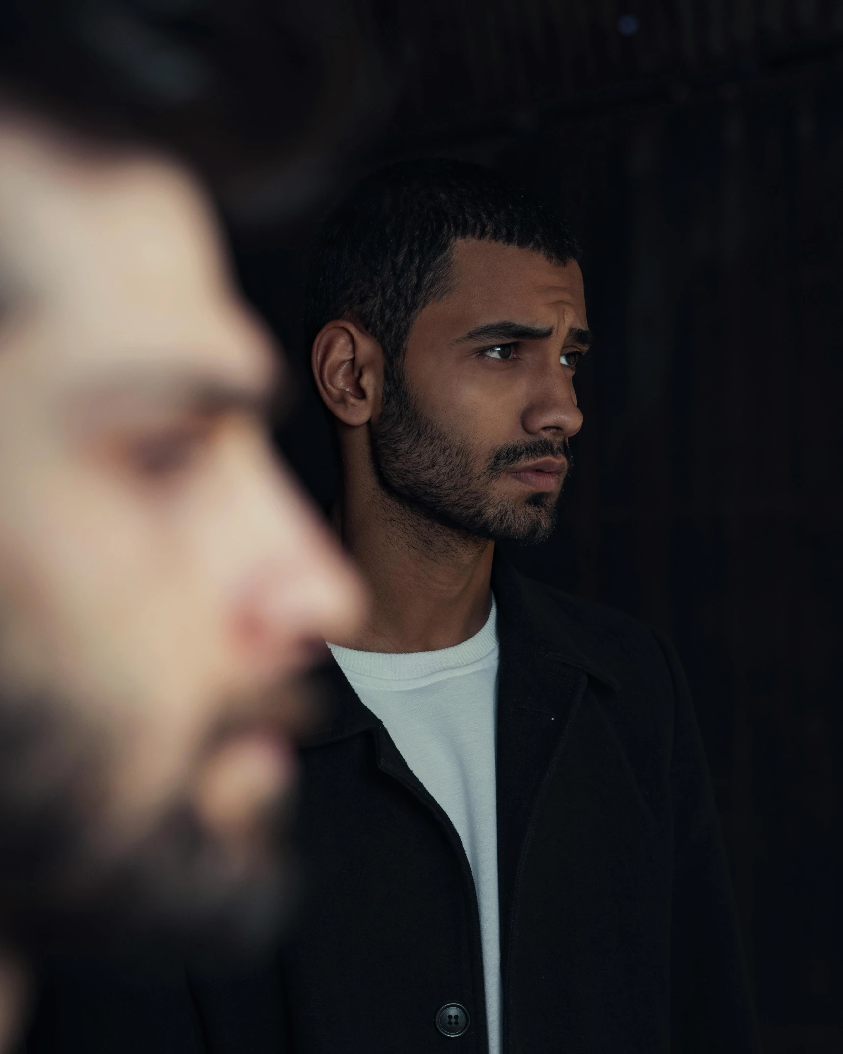 two men standing next to each other in a dark room, an album cover, by Ismail Acar, trending on pexels, mannerism, handsome face, an arab standing watching over, non binary model, foreground