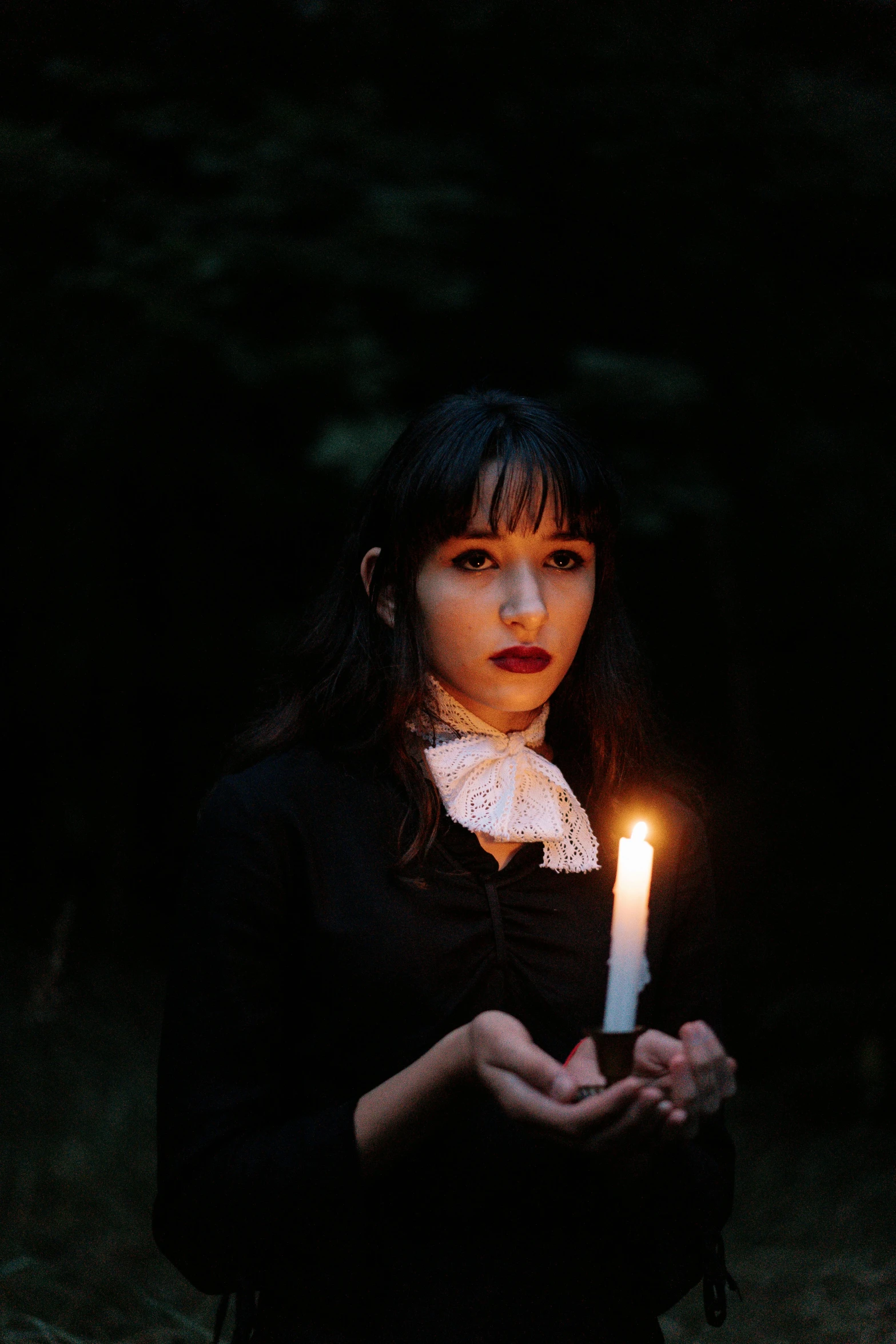 a woman holding a lit candle in her hands, an album cover, in a spooky forest, profile image