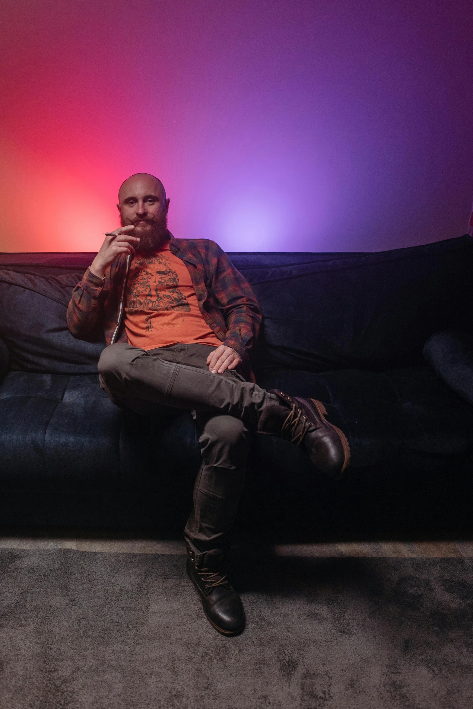 a man sitting on top of a black couch, a portrait, by David Begbie, pexels, maximalism, mac miller, color graded, diesel punk, darren aronofsky