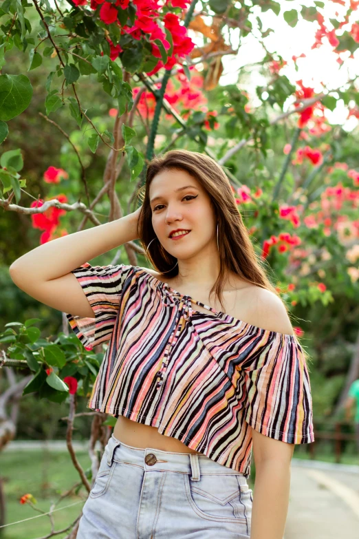 a woman posing for a picture in front of flowers, wearing a cropped tops, teen, striped, portrait image