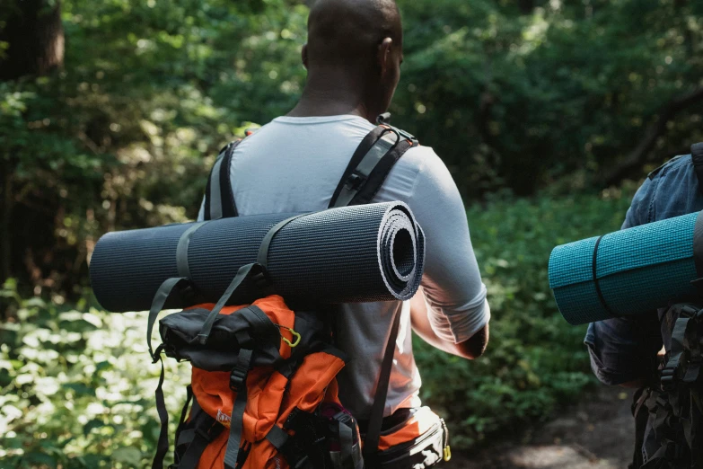 two men carrying yoga mats and backpacks in the woods, by Julian Allen, 4k photo”, close-up photo, thumbnail, al fresco