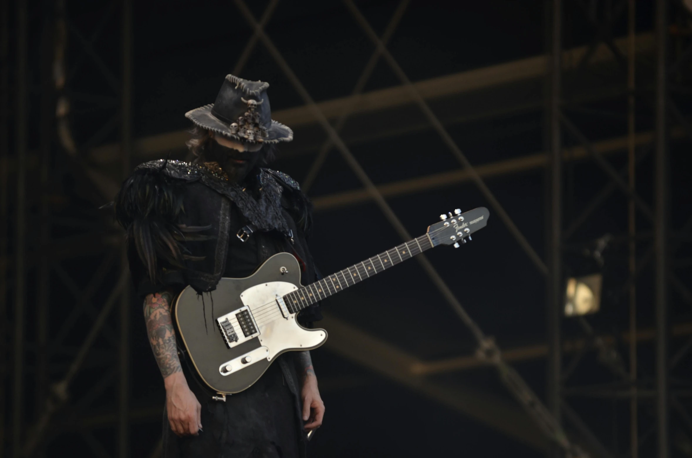 a man standing on top of a stage holding a guitar, pexels contest winner, antipodeans, he wears dark visors, pitchblack skin, archwizzard in a hat, zoomed out shot