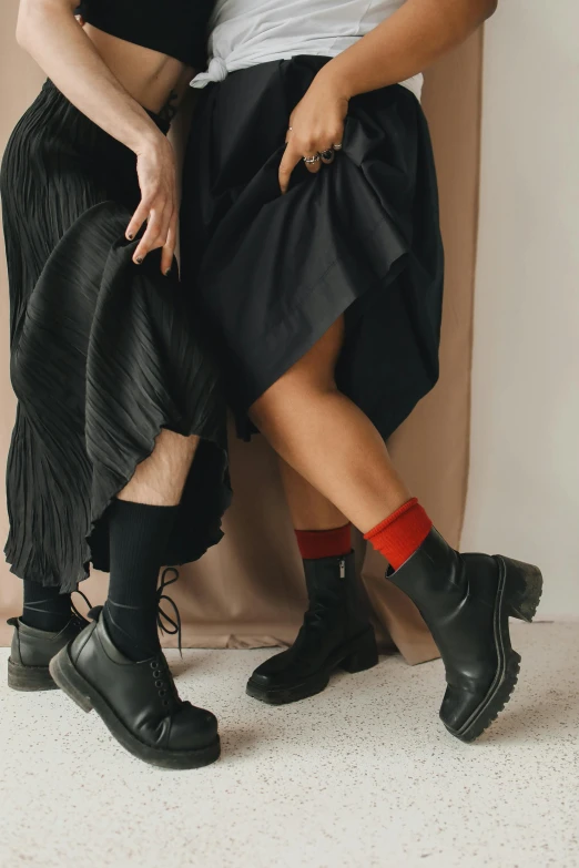 a couple of women sitting next to each other, by Julia Pishtar, trending on pexels, renaissance, wearing black boots, socks, black and red dress, lookbook