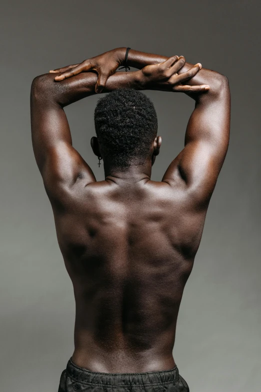 a man standing with his back to the camera, ebony skin, armpit, lean and toned, with grey skin