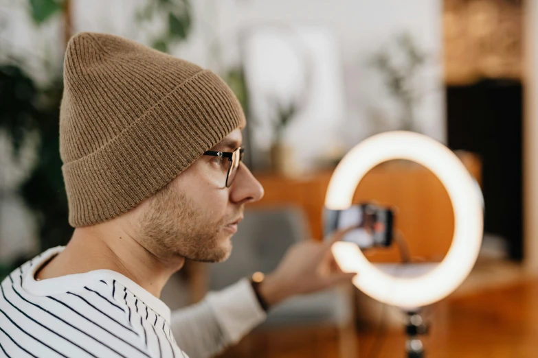 a man taking a picture of himself in a mirror, trending on pexels, beanie, a glowing halo, with professional lighting, product introduction photo