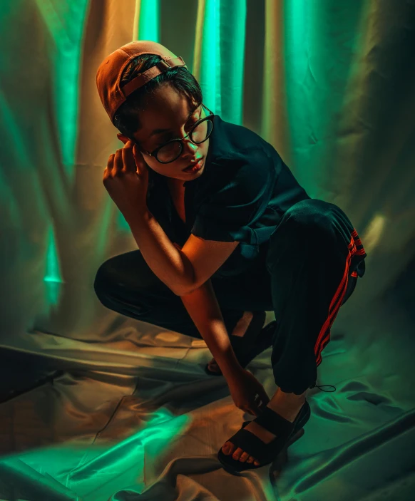 a woman kneeling on a sheet in front of a green light, by Andrew Stevovich, pexels contest winner, androgynous person, orange teal lighting, riyahd cassiem, woman in streetwear