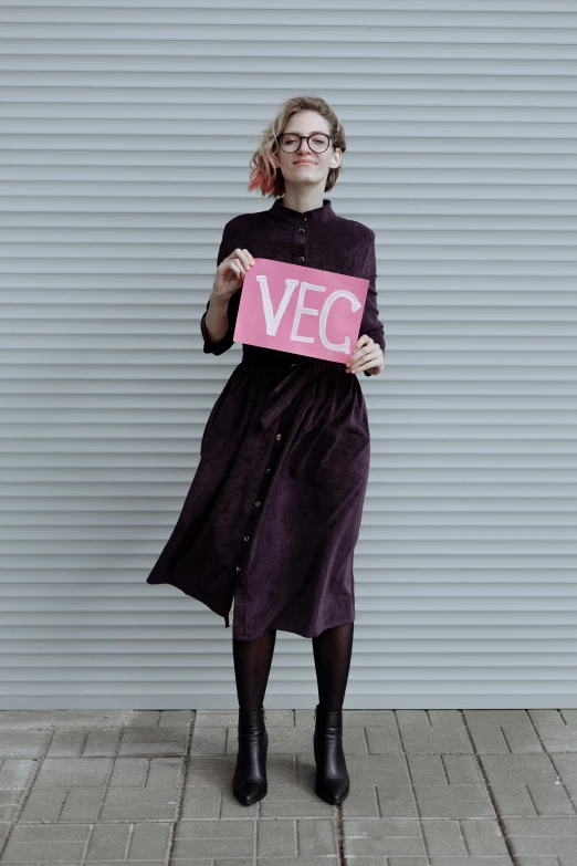 a woman holding a sign that says vega, inspired by Elke Vogelsang, visual art, dressed in velvet, (neotokyo), lookbook, very comfy]