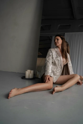 a woman sitting on the floor with her legs crossed, inspired by Elsa Bleda, renaissance, wearing a fancy jacket, sexy body, on a white table, glistening body