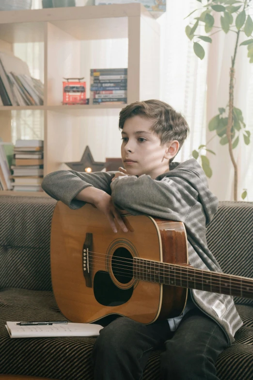 a boy sitting on a couch with a guitar, looking off to the side, filmstill, taken in 2 0 2 0, hd”