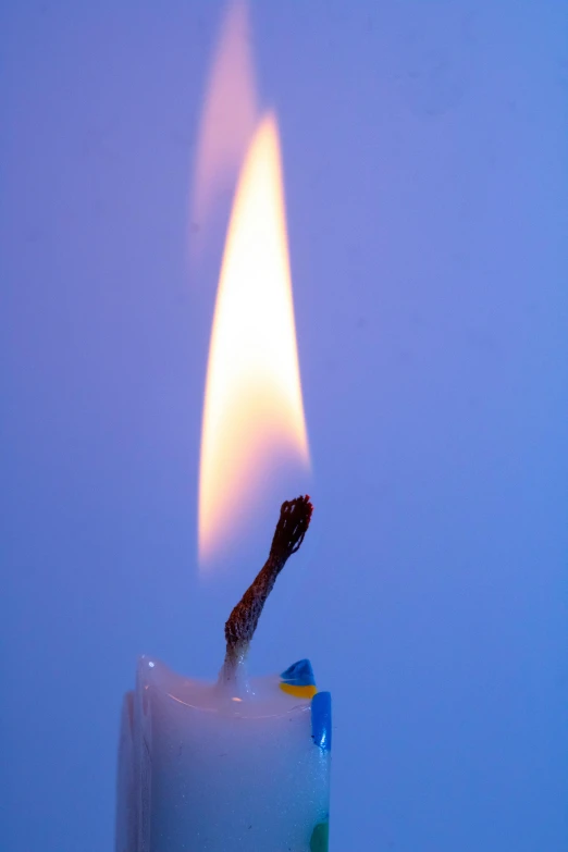 a lit candle in front of a blue background, the pyro, close up angle, profile image, lit from above