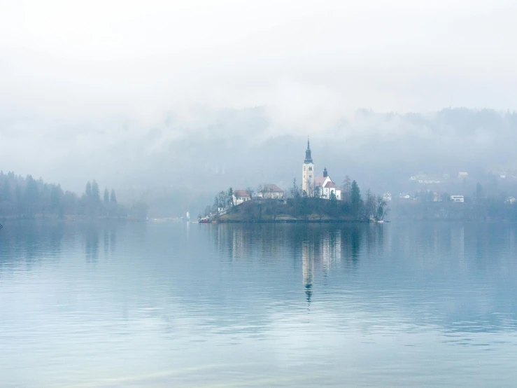 a small island in the middle of a lake, by Matija Jama, pexels contest winner, romanticism, white church background, light grey mist, view from a distance, slovenian