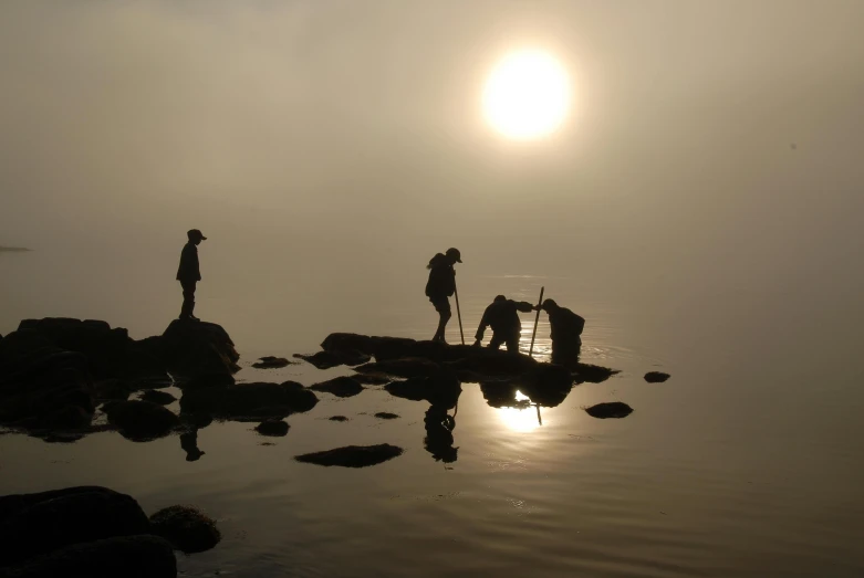 a group of people standing next to a body of water, a picture, foggy at dawn, humans exploring, maintenance photo, geology