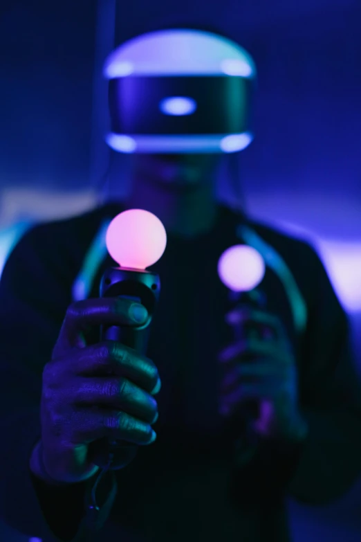 a man wearing a virtual reality headset in a dark room, inspired by Beeple, pexels, dark blue spheres fly around, holding controller, purple, tech demo