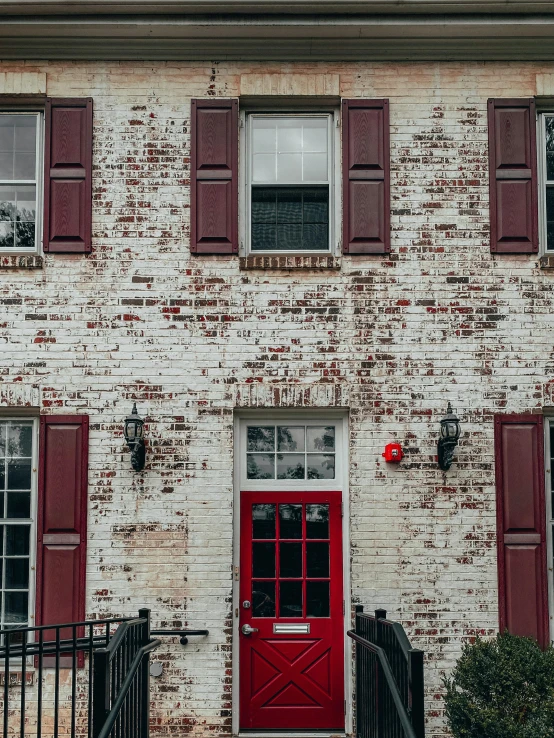 a brick building with red shutters and a red door, a photo, by Carey Morris, pexels contest winner, trending on vsco, casually dressed, white building, r / paintedminis